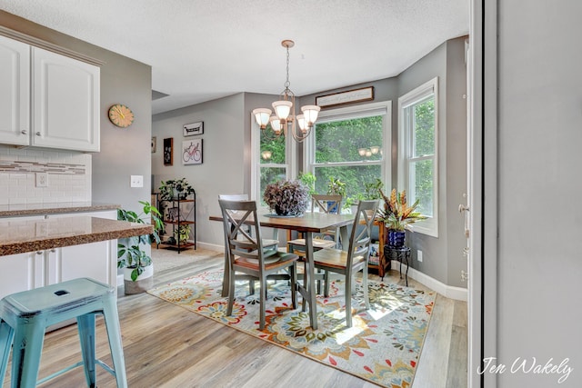 278 Caravan Rd, Norton Shores, MI 49441 - dining space with a chandelier, light wood-style flooring, and a textured ceiling