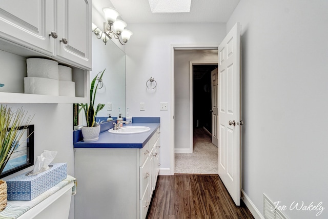 278 Caravan Rd, Norton Shores, MI 49441 - bathroom with vanity, wood finished floors, a skylight, and a chandelier