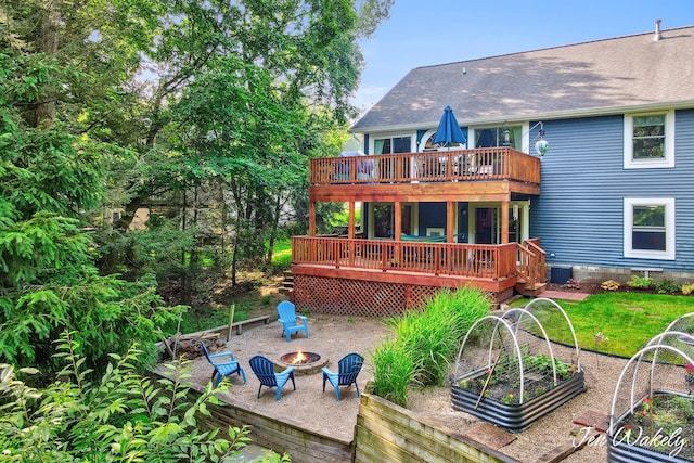 278 Caravan Rd, Norton Shores, MI 49441 - rear view of property featuring a vegetable garden, a fire pit, a deck, and a shingled roof