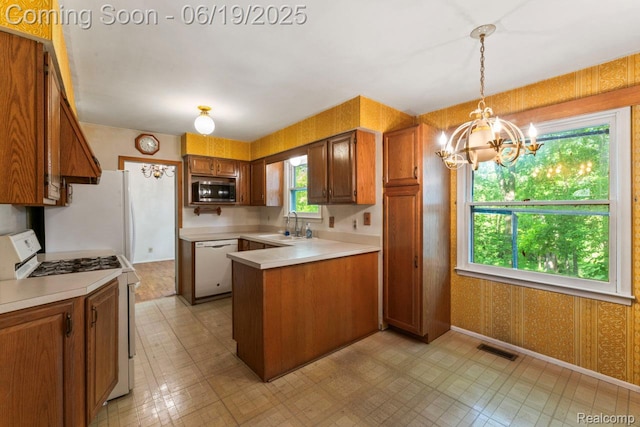 12260 Dollar Lake Dr, Fenton, MI 48430 - kitchen featuring white appliances, brown cabinets, a chandelier, a peninsula, and wallpapered walls