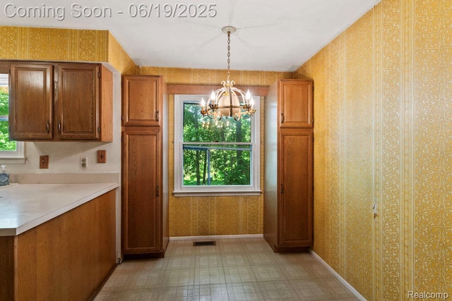 12260 Dollar Lake Dr, Fenton, MI 48430 - kitchen with a chandelier, brown cabinets, plenty of natural light, wallpapered walls, and light countertops