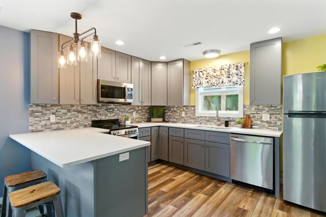 8368 N 46th St, Augusta, MI 49012 - kitchen featuring appliances with stainless steel finishes, gray cabinetry, a peninsula, a breakfast bar area, and wood finished floors