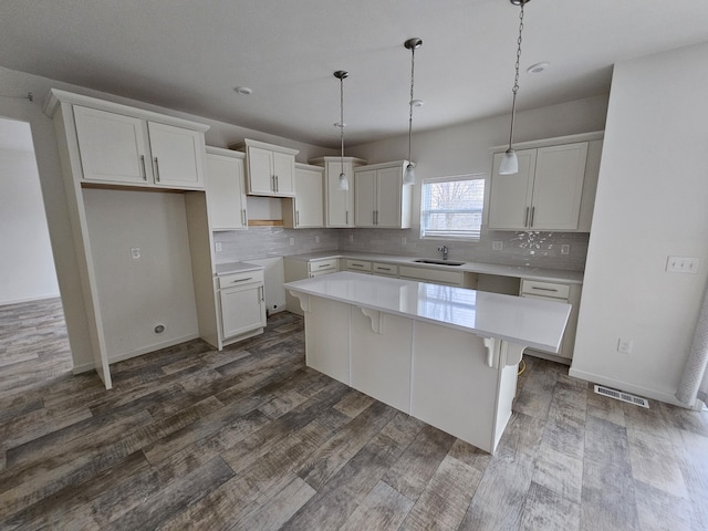 8781 Prairie Stone Dr SW, Byron Center, MI 49315 - kitchen with a kitchen island, decorative backsplash, white cabinets, and dark wood-style flooring
