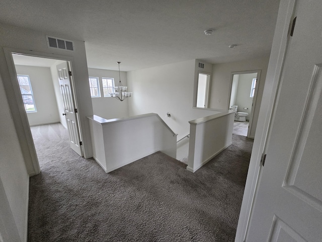 8781 Prairie Stone Dr SW, Byron Center, MI 49315 - hall featuring an upstairs landing, dark carpet, and a chandelier