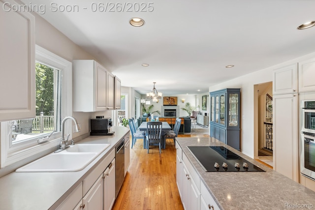 5520 Huron Hills Dr, Commerce Twp, MI 48382 - kitchen featuring appliances with stainless steel finishes, white cabinetry, light wood-style flooring, a chandelier, and recessed lighting