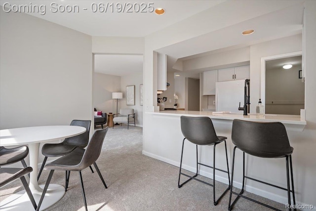 2755 Royal Ave, Berkley, MI 48072 - kitchen featuring freestanding refrigerator, a peninsula, a breakfast bar area, light colored carpet, and light countertops
