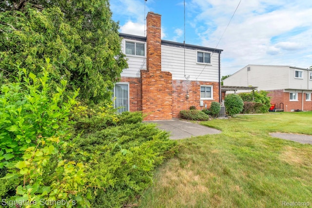 23719 Wendy Ln, Southfield, MI 48075 - rear view of house featuring brick siding, a chimney, and a lawn