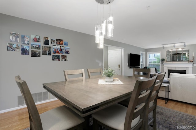 28185 Carlton Way Dr, Novi, MI 48377 - dining room with light wood finished floors, a chandelier, and a tiled fireplace