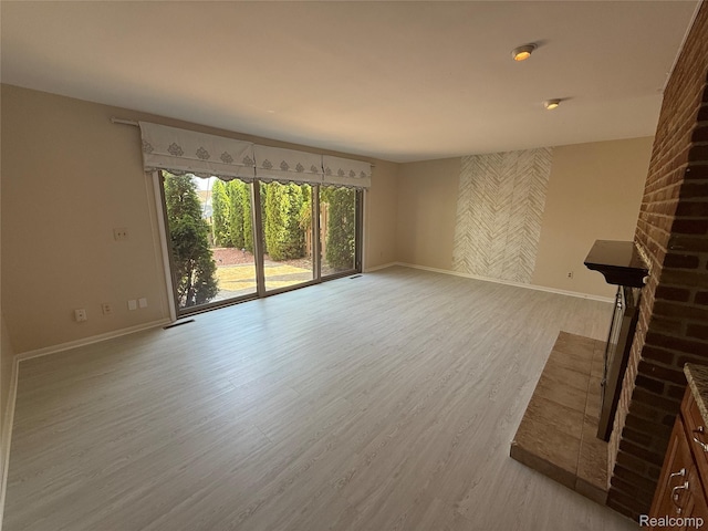 6352 Laurentian Ct, Flint, MI 48532 - unfurnished living room featuring light wood-style flooring and a brick fireplace