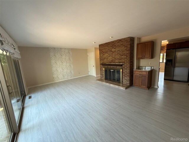 6352 Laurentian Ct, Flint, MI 48532 - unfurnished living room with light wood-style flooring and a brick fireplace