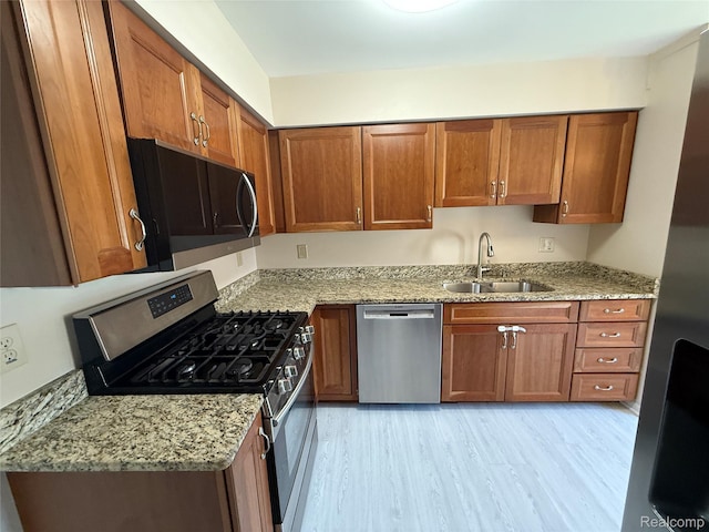 6352 Laurentian Ct, Flint, MI 48532 - kitchen with stainless steel appliances, brown cabinetry, light stone countertops, and light wood-style floors