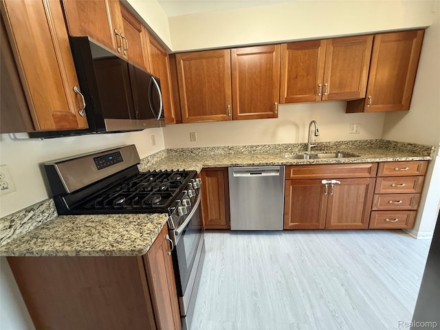 6352 Laurentian Ct, Flint, MI 48532 - kitchen with stainless steel appliances, brown cabinetry, light stone countertops, and light wood-style floors