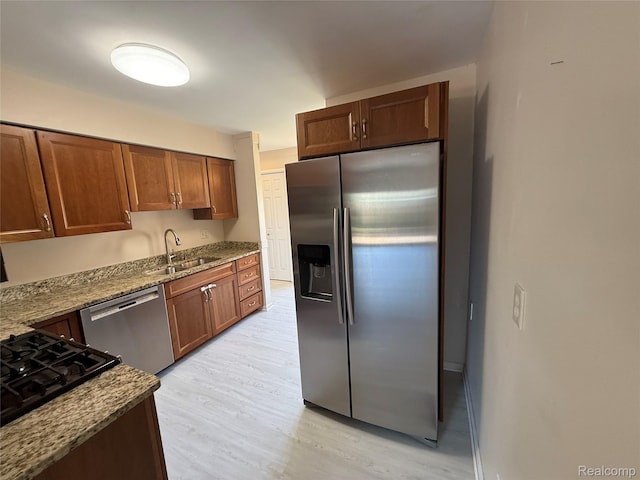 6352 Laurentian Ct, Flint, MI 48532 - kitchen featuring appliances with stainless steel finishes, light wood finished floors, dark stone countertops, and brown cabinetry
