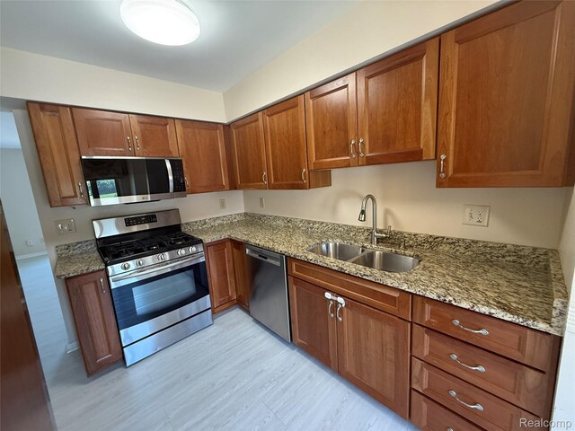 6352 Laurentian Ct, Flint, MI 48532 - kitchen with stainless steel appliances, brown cabinetry, light stone countertops, and light wood-style flooring