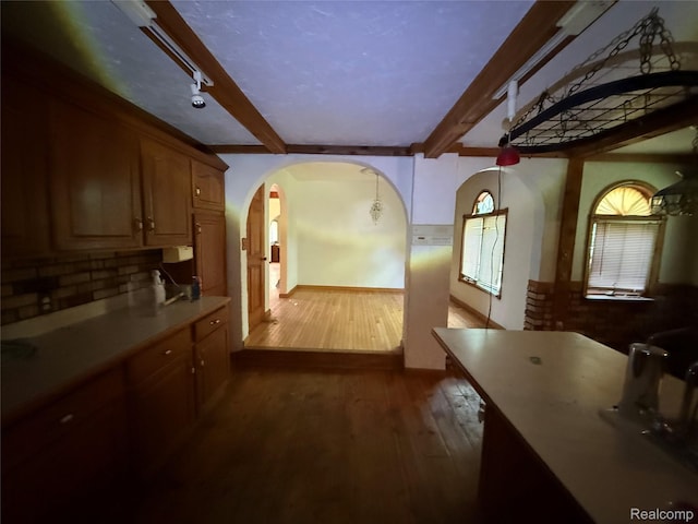 6456 W Court St, Flint, MI 48532 - kitchen featuring beamed ceiling, arched walkways, dark wood-type flooring, tasteful backsplash, and light countertops