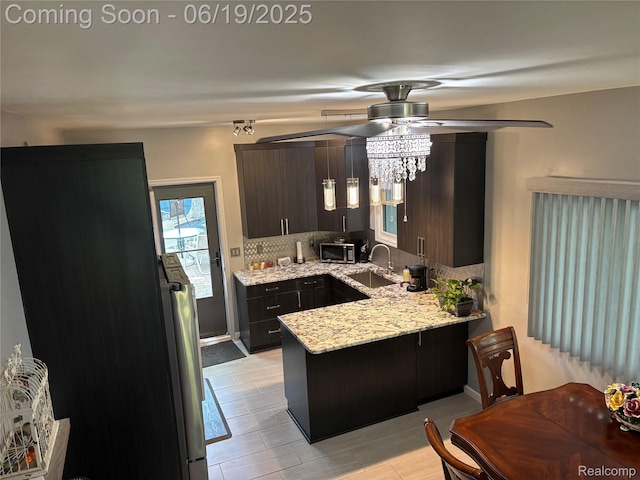 4817 Hickory Dr, Highland, MI 48356 - kitchen featuring a peninsula, a ceiling fan, tasteful backsplash, stainless steel microwave, and light stone counters