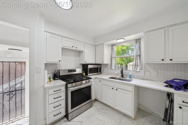15477 Lauder St, Detroit, MI 48227 - kitchen featuring appliances with stainless steel finishes, light marble finish floors, white cabinets, and decorative backsplash