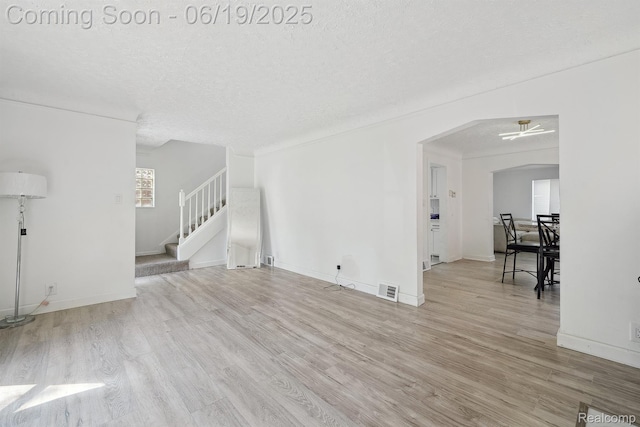 15477 Lauder St, Detroit, MI 48227 - unfurnished living room with wood finished floors, stairway, a textured ceiling, and arched walkways