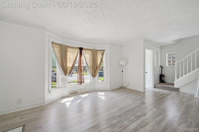 15477 Lauder St, Detroit, MI 48227 - unfurnished living room featuring a textured ceiling, healthy amount of natural light, stairs, and wood finished floors
