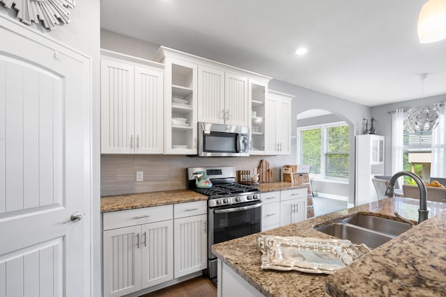 855 Cooks Crossing Dr SE, Byron Center, MI 49315 - kitchen with appliances with stainless steel finishes, arched walkways, white cabinets, tasteful backsplash, and glass insert cabinets