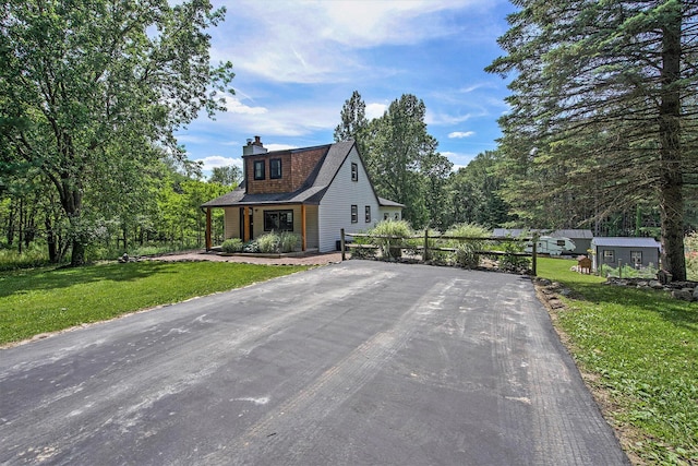 8041 Donovan Rd, Dexter, MI 48130 - view of front facade featuring a front yard, driveway, a chimney, a porch, and an outbuilding