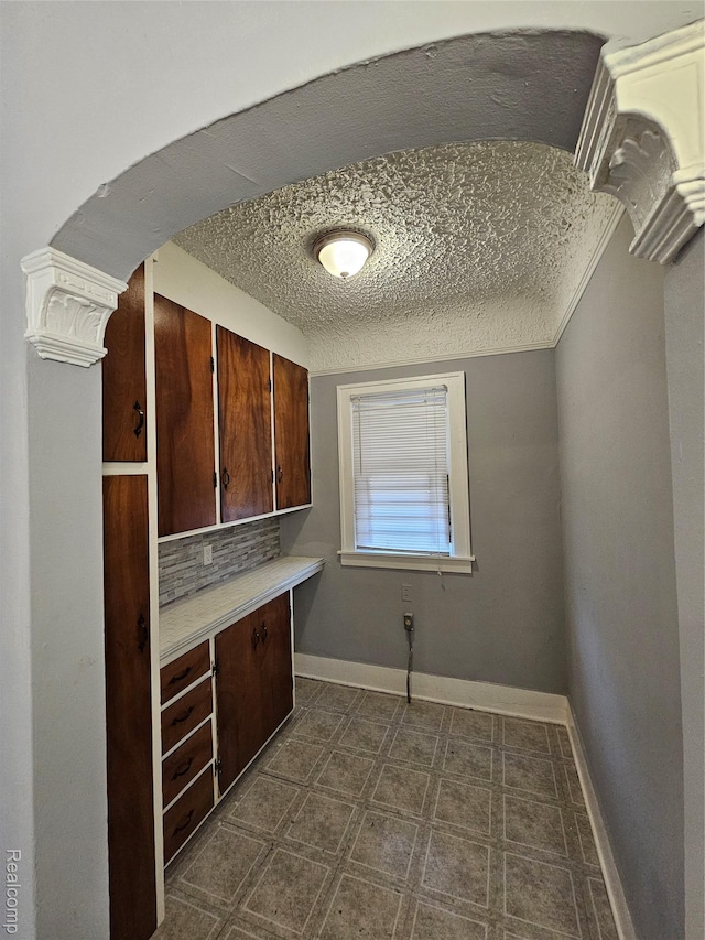 12645 Cloverlawn St, Detroit, MI 48238 - kitchen featuring light countertops, a textured ceiling, decorative backsplash, and arched walkways