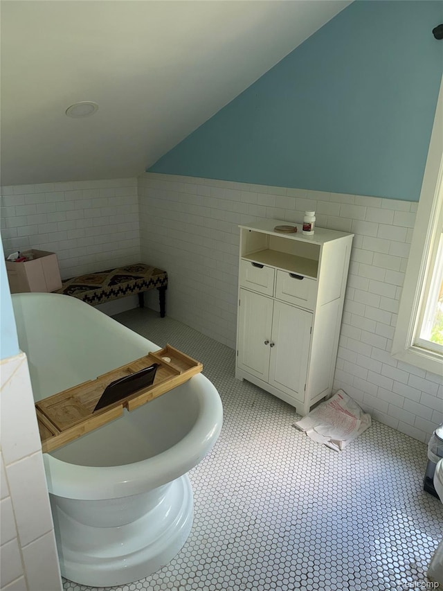 19374 Five Points St, Redford, MI 48240 - bathroom with tile walls, vaulted ceiling, tile patterned flooring, and a wainscoted wall