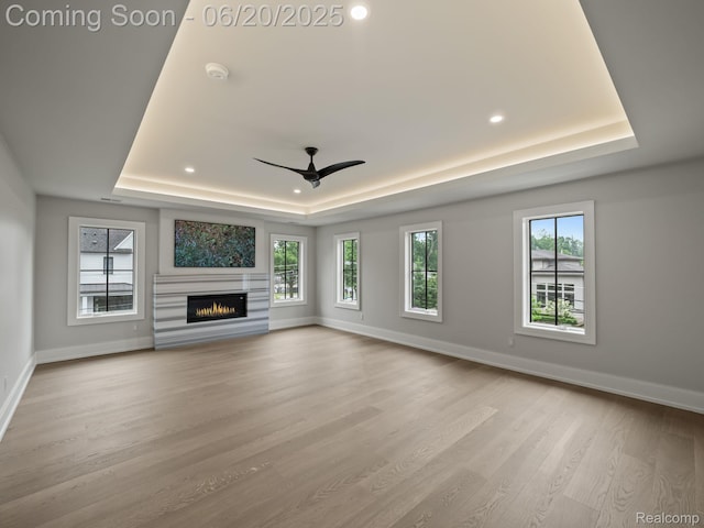 1120 Lyonhurst St, Birmingham, MI 48009 - unfurnished living room featuring a raised ceiling, light wood-type flooring, a warm lit fireplace, recessed lighting, and a ceiling fan