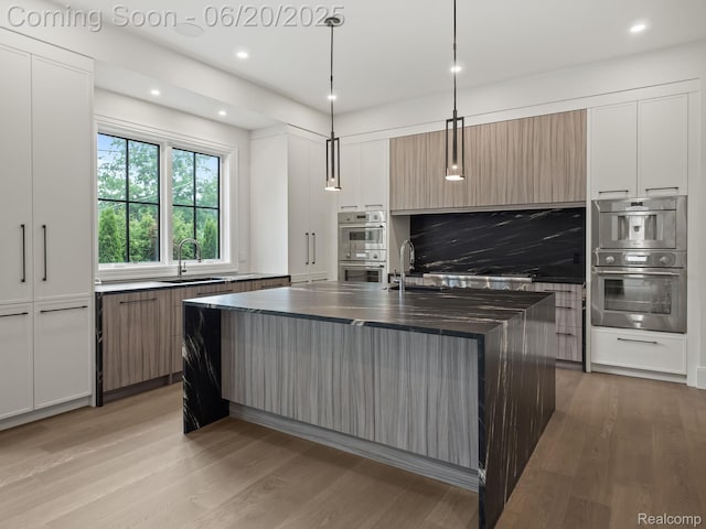 1120 Lyonhurst St, Birmingham, MI 48009 - kitchen with stainless steel double oven, dark countertops, modern cabinets, light wood-type flooring, and recessed lighting