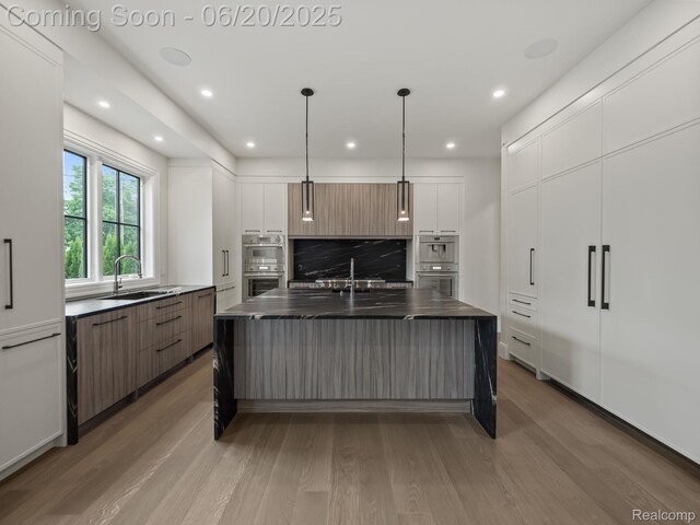 1120 Lyonhurst St, Birmingham, MI 48009 - kitchen with modern cabinets, stainless steel double oven, dark countertops, tasteful backsplash, and light wood finished floors
