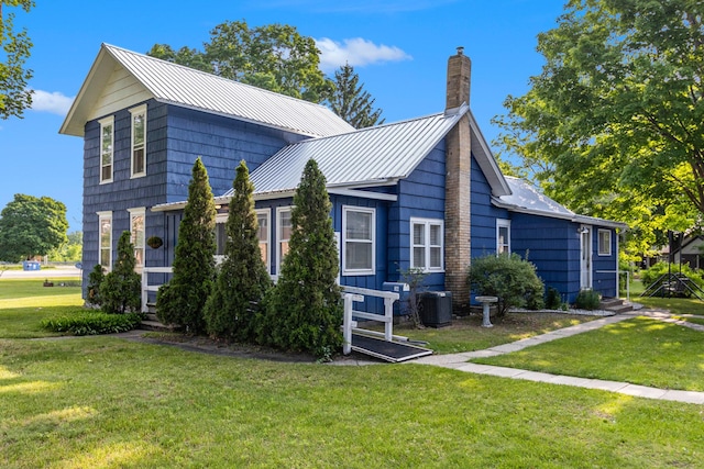 922 Marion Ave, Big Rapids, MI 49307 - view of side of property featuring a lawn, a chimney, a standing seam roof, and a metal roof