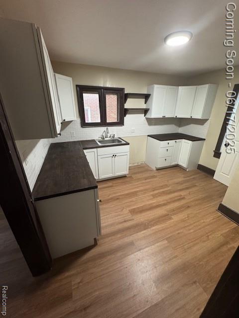 5215 Buckingham Ave, Detroit, MI 48224 - kitchen featuring dark countertops, white cabinetry, and light wood-style flooring