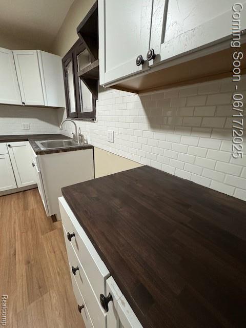 5215 Buckingham Ave, Detroit, MI 48224 - kitchen with light wood-style floors, tasteful backsplash, white cabinets, and dark countertops