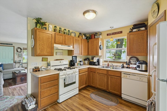 857 Kalamazoo St, South Haven, MI 49090 - kitchen with white appliances, under cabinet range hood, light countertops, light wood-style flooring, and hanging light fixtures