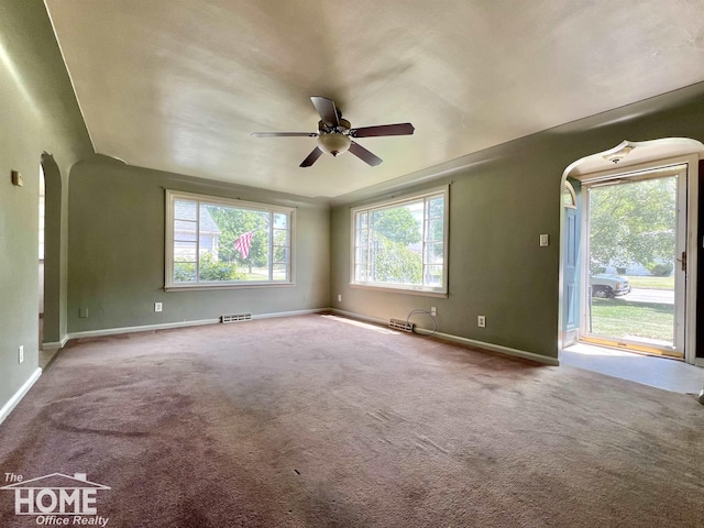 435 Brandon St, Owosso, MI 48867 - carpeted empty room with arched walkways and ceiling fan