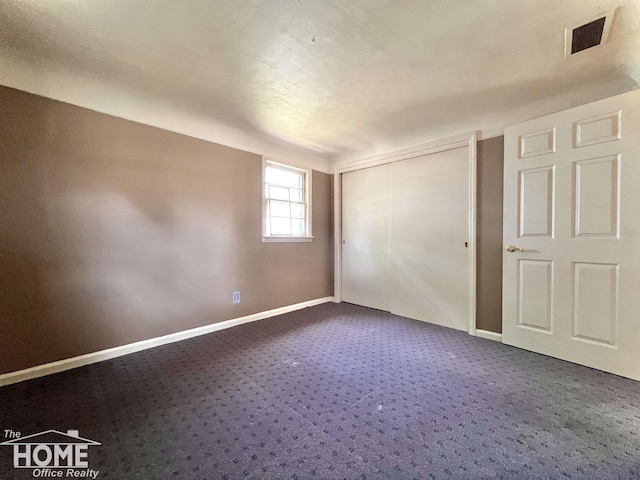 435 Brandon St, Owosso, MI 48867 - unfurnished bedroom featuring dark colored carpet and a closet