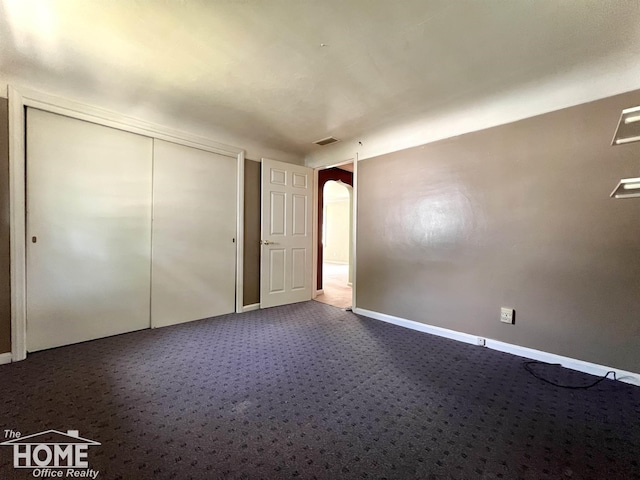 435 Brandon St, Owosso, MI 48867 - unfurnished bedroom with carpet floors, arched walkways, and a closet