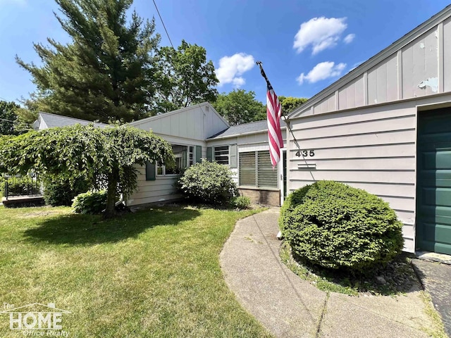 435 Brandon St, Owosso, MI 48867 - view of side of property with board and batten siding and a yard