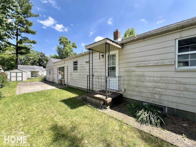 435 Brandon St, Owosso, MI 48867 - rear view of property featuring a storage shed, a lawn, a chimney, and a patio