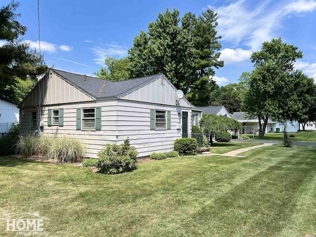 435 Brandon St, Owosso, MI 48867 - view of home's exterior featuring board and batten siding, a lawn, and a shingled roof