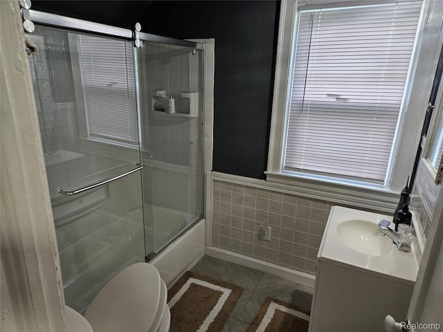 4294 W Buena Vista St, Detroit, MI 48238 - bathroom with tile patterned floors, tile walls, shower / bath combination with glass door, vanity, and a wainscoted wall