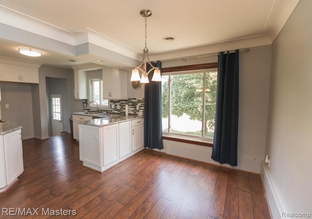 5820 Houghten Dr, Troy, MI 48098 - kitchen with a peninsula, white cabinetry, light stone countertops, tasteful backsplash, and dark wood-type flooring
