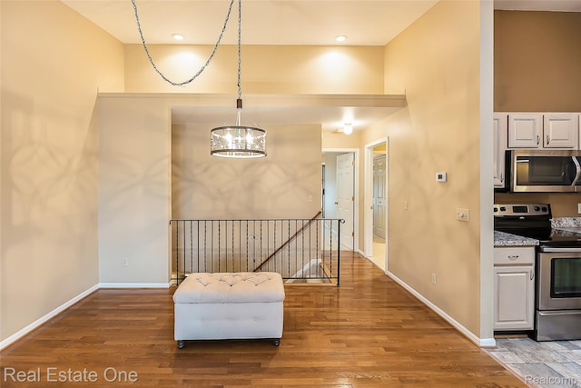 62622 Raleigh Ct Unit 4, South Lyon, MI 48178 - interior space with stainless steel appliances, a chandelier, wood finished floors, white cabinetry, and pendant lighting