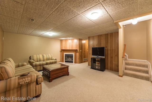 62622 Raleigh Ct Unit 4, South Lyon, MI 48178 - living room featuring carpet floors, a tile fireplace, wood walls, and stairs