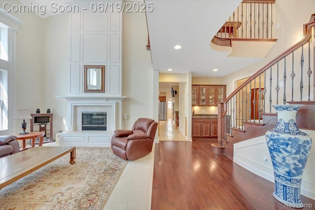43443 Mclean Ct, Novi, MI 48375 - living room featuring wood finished floors, stairway, a high ceiling, a glass covered fireplace, and recessed lighting