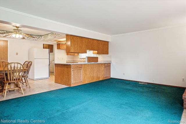 13142 Boca Grande Dr, Sterling Heights, MI 48312 - kitchen with freestanding refrigerator, a peninsula, a ceiling fan, brown cabinets, and light carpet