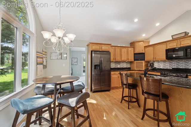 4273 Fairway Ln, Jackson, MI 49201 - kitchen with stainless steel refrigerator with ice dispenser, black microwave, backsplash, high vaulted ceiling, and plenty of natural light
