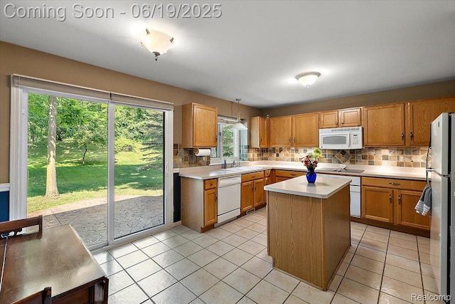 2082 Avon Lake Ln, Rochester Hills, MI 48307 - kitchen featuring white appliances, backsplash, light countertops, a center island, and brown cabinets