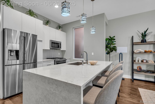 2648 John R St, Detroit, MI 48201 - kitchen with appliances with stainless steel finishes, dark wood-type flooring, white cabinets, light stone counters, and a kitchen island with sink