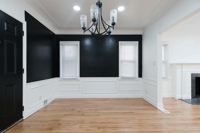 15821 Kentfield St, Detroit, MI 48223 - unfurnished dining area with a chandelier, a fireplace, light wood-style floors, a wainscoted wall, and recessed lighting
